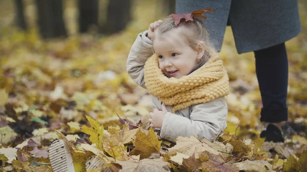 Niña rubia juega con hojas en el parque de otoño — Foto de Stock