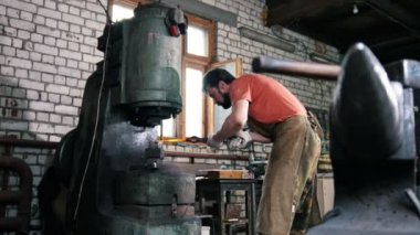 Erkek demirci metal otomatik bir çekiç yardımıyla şekil verir