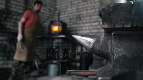アンビルは、ストーブの近くに立っている鍛冶屋の背景です。ぼやけています。 — ストック動画
