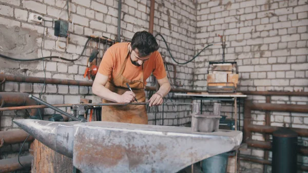 Herrero está doblando varilla de hierro con martillo taller de metal, de cerca — Foto de Stock