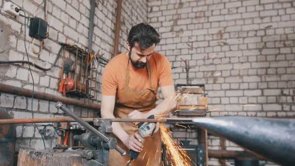 Barbudo herrero forjando un cuchillo con sierra circular —  Fotos de Stock