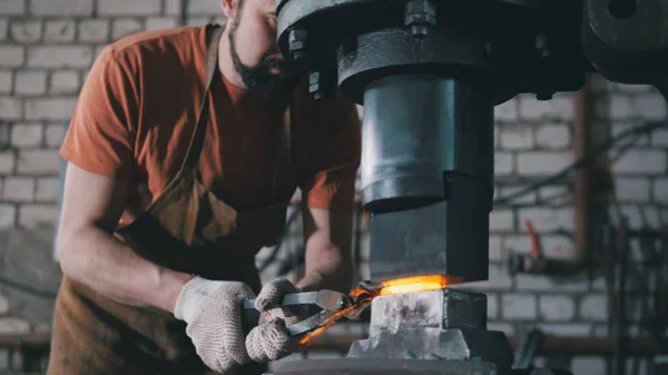 Atelier d'un forgeron. Un homme met une pièce forgée sous un marteau automatique — Photo