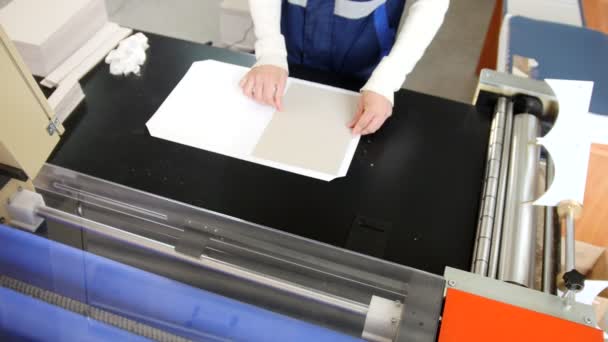 Оператор поліграфічного виробництва тягне друкований аркуш паперу — стокове відео