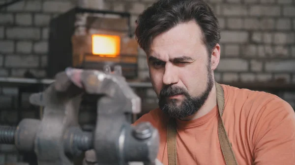 Herrero dobla cuchillo de metal con gripe en taller forja, retrato — Foto de Stock