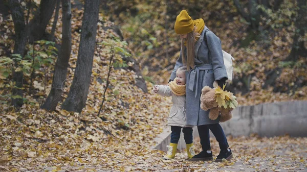 Mujer con hija pequeña en el parque de otoño entre hojas amarillas — Foto de Stock