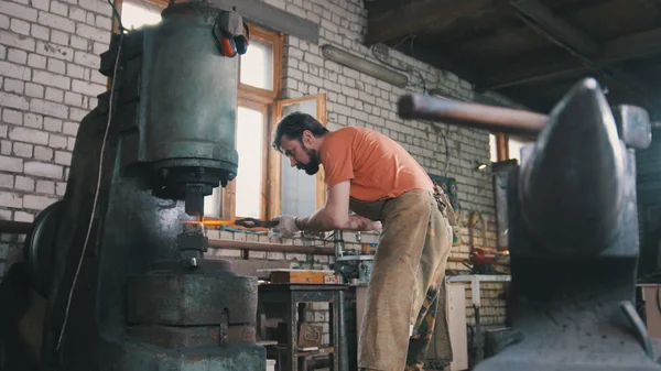 男の鍛冶屋は機械ハンマーで金属を偽造します。 — ストック写真
