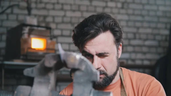 Herrero dobla cuchillo de metal con gripe en taller forja, retrato —  Fotos de Stock