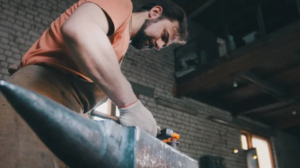 Herrero dobla cuchillo de metal con gripe en taller forja, retrato — Foto de Stock