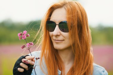 Kızıl saçlı kız Motorcu bir çiçek bir eldiven elinde tutuyor