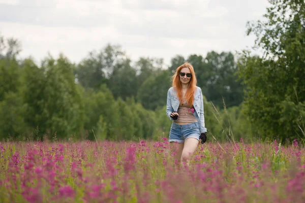 Krásná rusovlasá dívka chůze na Květinová louka — Stock fotografie