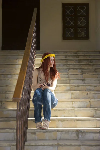 Una ragazza si siede sulle scale e guarda fuori dalla finestra — Foto Stock