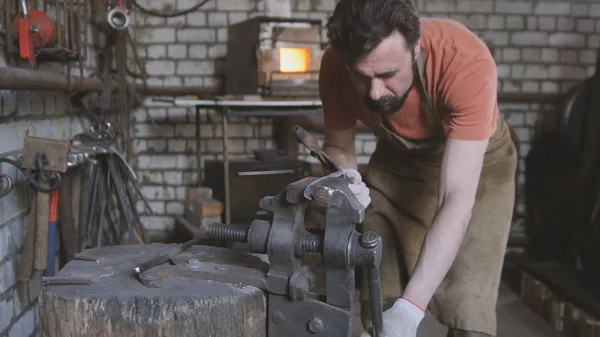 Giovane uomo muscoloso che lavora su un fabbro con metallo — Foto Stock