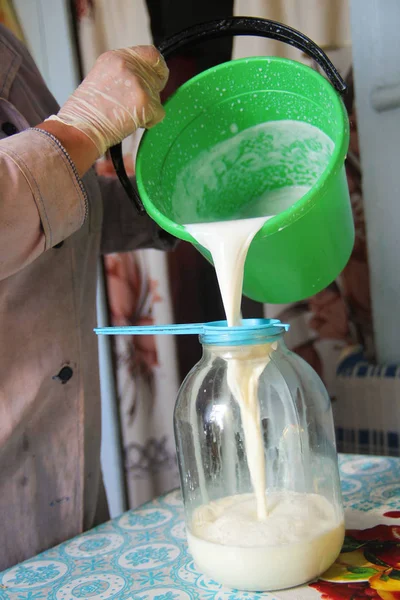 La leche fresca se vierte del cubo en un frasco de vidrio — Foto de Stock