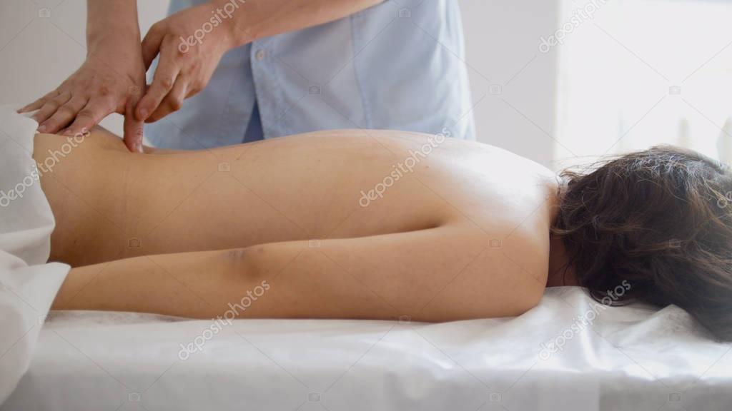 The doctor massages the womans back on the table in the Tibetan medicine cabinet