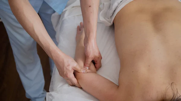 Mulher em uma mesa de fisioterapia durante uma massagem no consultório médico — Fotografia de Stock