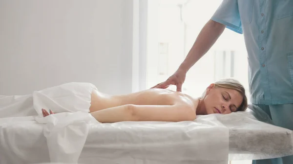 La mujer joven se acuesta en una mesa de masaje - terapia manual terapéutica —  Fotos de Stock