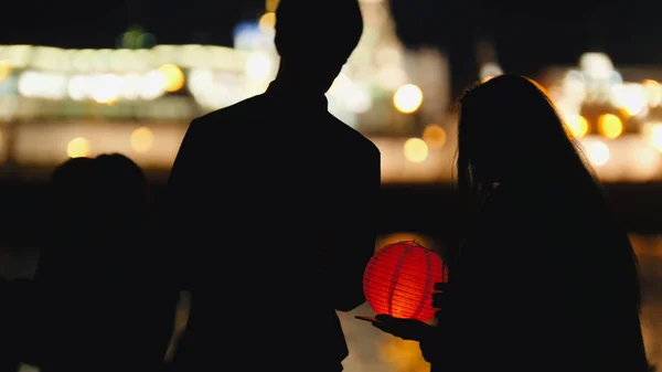 Silhouet liefdevolle paar op festival van drijvende lantaarns in de buurt van rivier bij nacht — Stockfoto