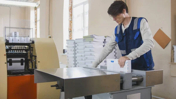 Processo di stampa - i lavoratori inseriscono fogli di carta nella pressa industriale — Foto Stock