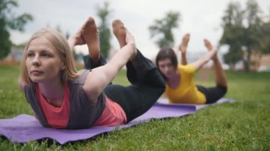 İki genç kadın parkta esneklik için eğitim gerçekleştirir