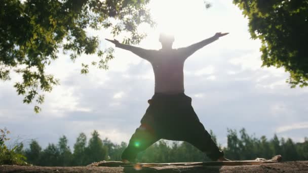 Силует молодого спортсмена-інструктора, що практикує йогу на світанку — стокове відео