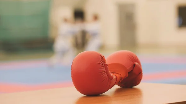 Rote Handschuhe für Karatetraining auf Tatami während des Trainings, defokussiert — Stockfoto