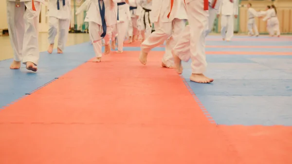 Karate träning - unga idrottsmän i kimono körs på tatami i gymmet — Stockfoto