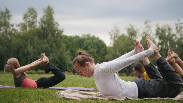 Йога-тренировка на свежем воздухе - группа мужчин выполняет упражнения на гибкость — стоковое видео