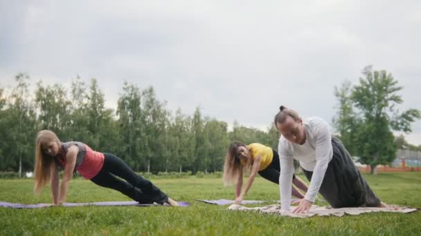Yoga en el parque matutino - instrctor y chica realiza meditación en el parque — Vídeos de Stock