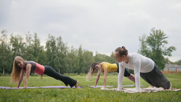 Yoga al aire libre - instrctor y chica realiza meditación en el parque — Vídeos de Stock