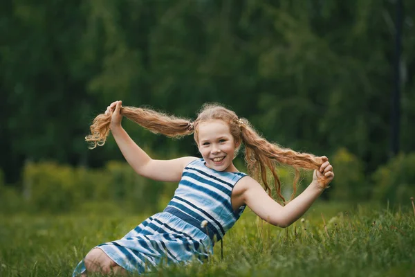 青い夏のドレスを着て笑顔の子女の子が公園で遊んでいます。 — ストック写真