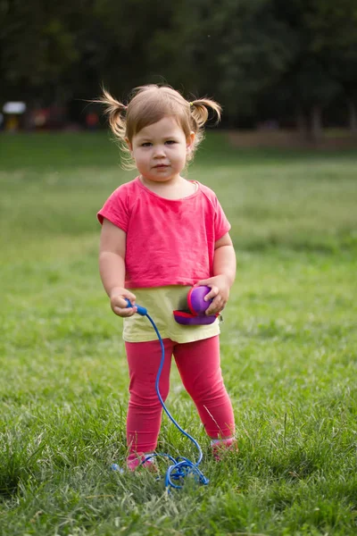 緑の草の前に公園で遊ぶピンクのドレスかわいい幼児女の子 — ストック写真