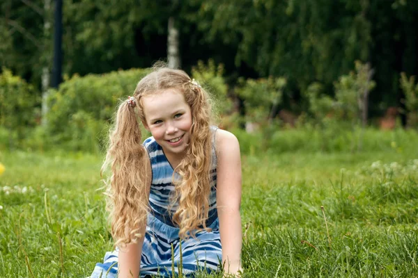 Sonriente niña con vestido azul de verano está posando en el parque — Foto de Stock