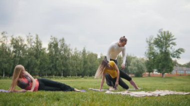 Adam eğitmen genç kadınlar için esneklik - sabah parkta yoga pratik eğitim