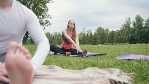 Yogaövningar i park - unga idrottsmän utför flexibilitet utbildning utomhus — Stockvideo