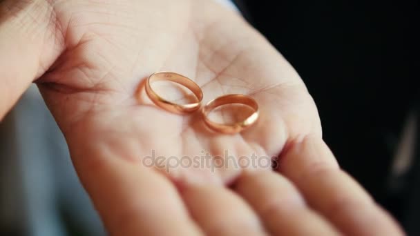 Свадьба - жених держит золотые обручальные кольца на ладони — стоковое видео