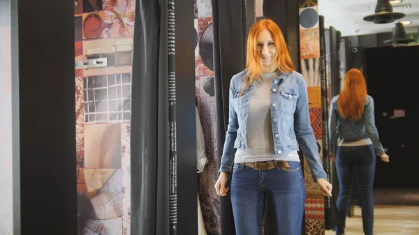 Hübsche Frau probiert Jeansjacke in Umkleidekabine des Ladens an — Stockfoto