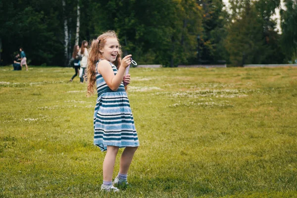 青い夏のドレスを着て笑顔の子女の子が公園で遊んでいます。 — ストック写真
