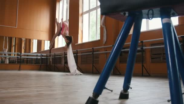 Дівчина-спортсменка тренує акробатику в спортзалі - рожевий костюм — стокове відео