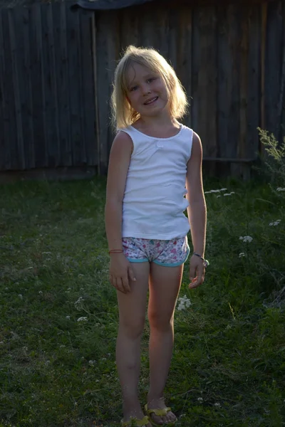 Porträtt av liten blond flicka poserar i Gårds planen, sommar byn, solnedgång — Stockfoto