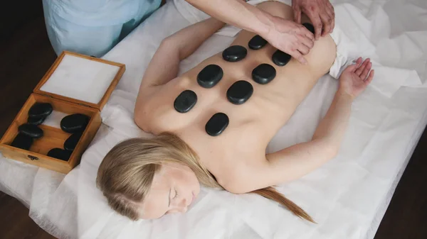 Stone-therapy - doctor puts on the stones on back girls — Stock Photo, Image