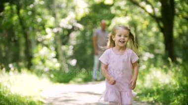 Küçük bir kız kameranın Park, doğru çalışır ağır çekim