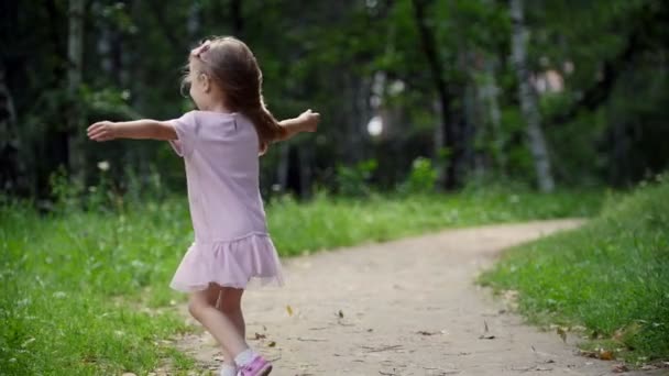Entzückendes blondes Kindermädchen dreht sich im Park in Zeitlupe — Stockvideo