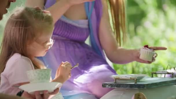 Щаслива сім'я в парку - батько і дочка п'ють чай на відкритому повітрі в зеленому парку — стокове відео