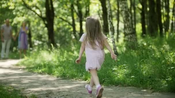 Ein kleines blondes Mädchen läuft an sonnigen Tagen in Zeitlupe durch den Park — Stockvideo