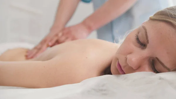 Aantrekkelijke jonge vrouw ontvangen van massage in de spa. Ontspanning behandeling van schouders, close-up — Stockfoto