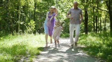 Mutlu aile - küçük kız çalışan doğru kameranın Park, ağır çekim
