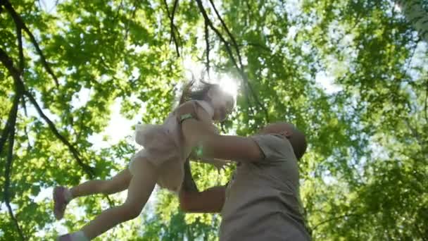 Otec si hraje s dcerou v parku - hází do své děťátko, pomalý pohyb — Stock video