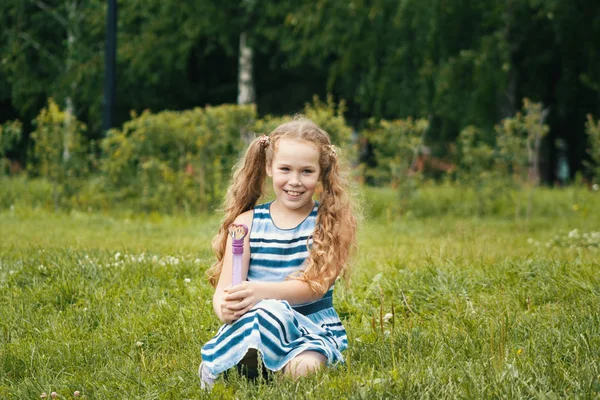 Sonriente niña con vestido azul de verano está jugando en el parque — Foto de Stock