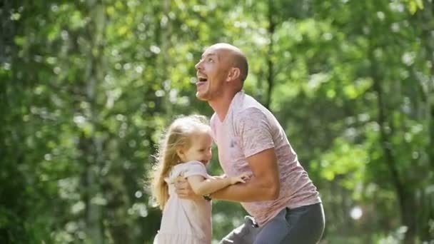 Šťastná rodina: otec a jeho šťastná dcera dítě v létě park - pomalý pohyb — Stock video