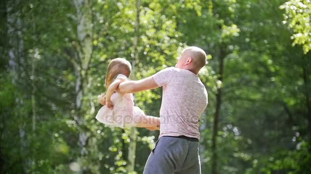 Barn tjej med far i park - pappa snurrar hennes lilla flicka, slow motion — Stockvideo